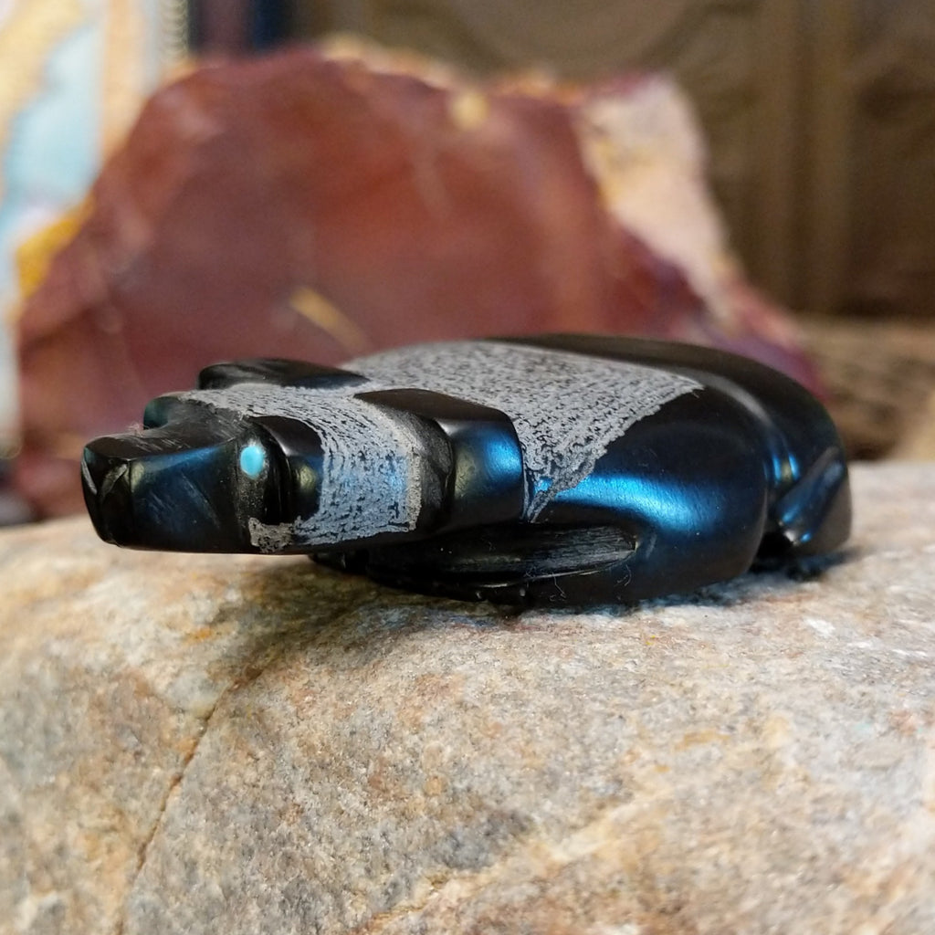 Black marble carved in the shape of a panda laying down.