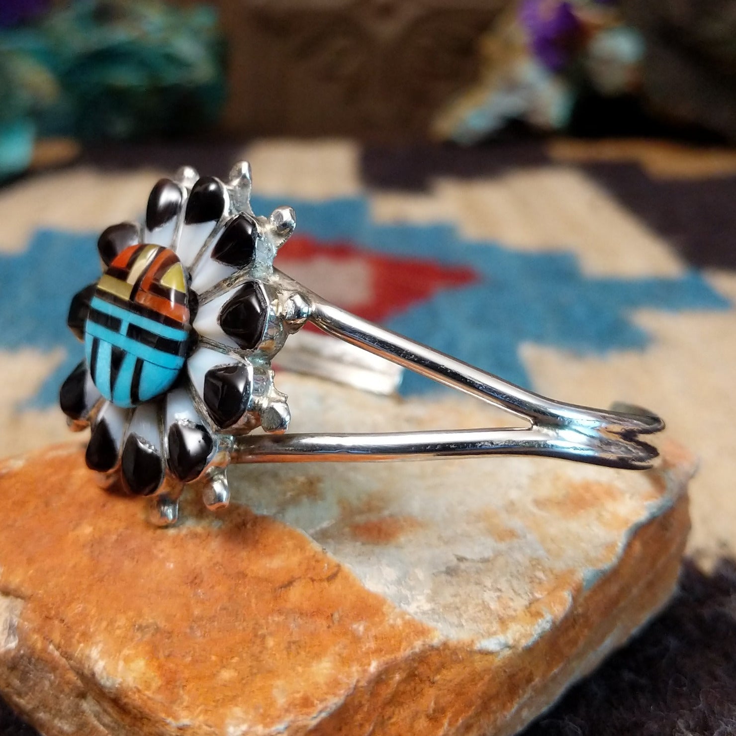Zuni Sunface cuff by D., featuring a traditional Sunface design with intricate inlay work and handcrafted Southwestern-inspired metalwork.  Side view.