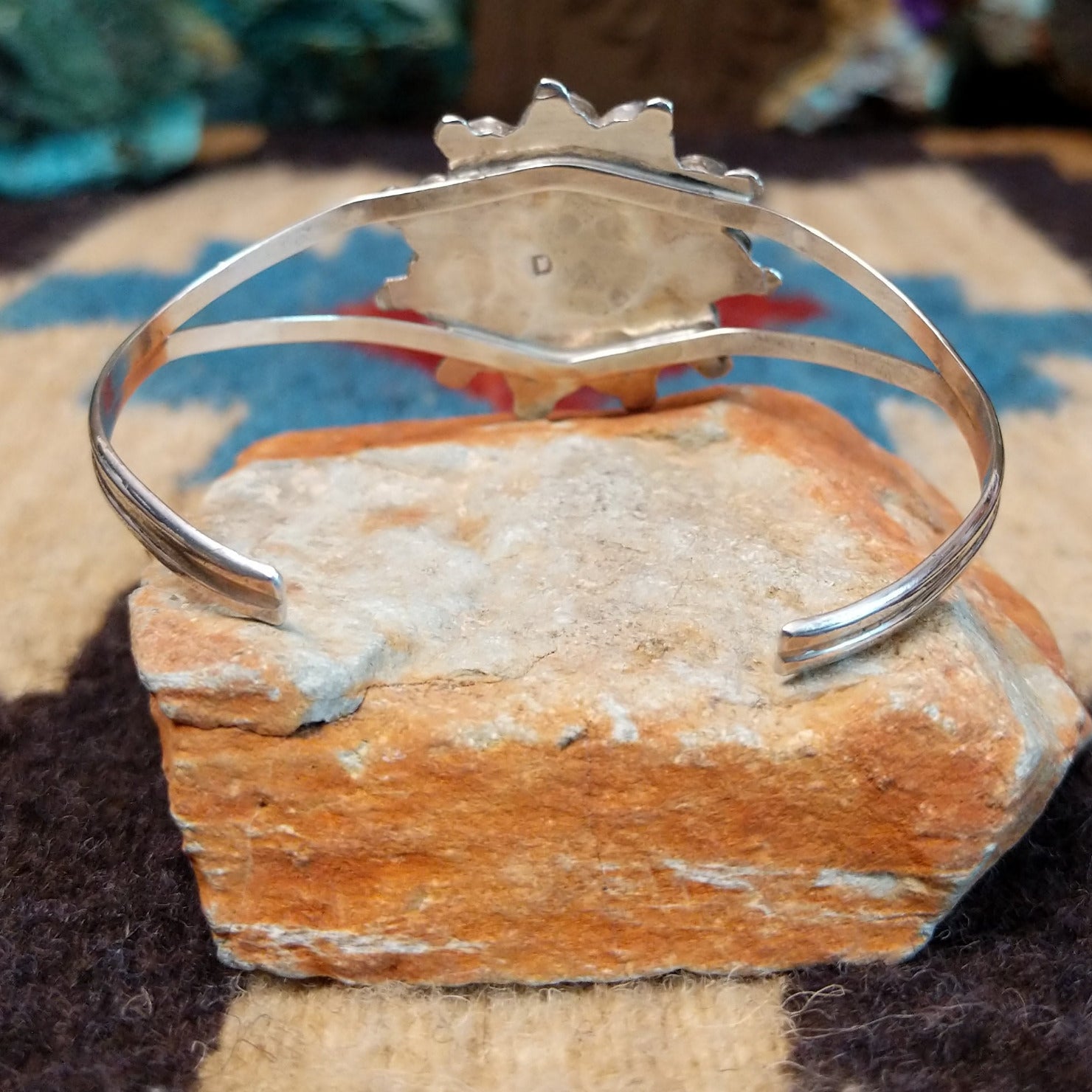 Zuni Sunface cuff by D., featuring a traditional Sunface design with intricate inlay work and handcrafted Southwestern-inspired metalwork.  Underside view.