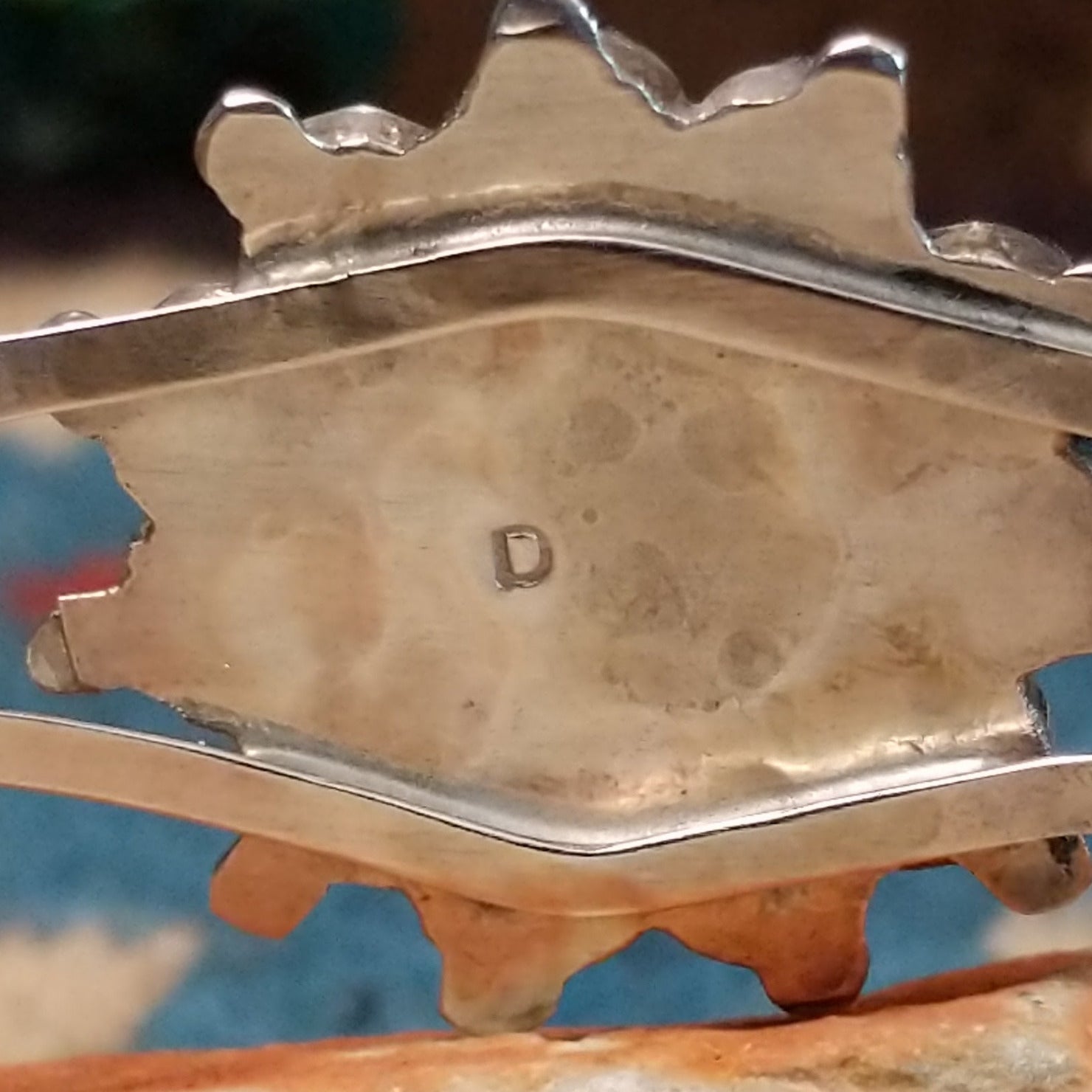 Zuni Sunface cuff by D., featuring a traditional Sunface design with intricate inlay work and handcrafted Southwestern-inspired metalwork.  Artisan stamp.