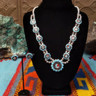 Zuni Sunface Sterling Silver necklace and matching earrings by Marisa Selecion, featuring turquoise, coral, black onyx, and mother of pearl, with detailed Sunface designs.