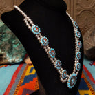 Zuni Sunface Sterling Silver necklace by Marisa Selecion, featuring turquoise, coral, black onyx, and mother of pearl, with detailed Sunface designs; side view.