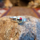 Sterling silver ring with sunface design crafted with turquoise, mother of pearl, black onyx, and coral that is framed by twisted rope detailing.