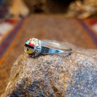 Sterling silver ring with sunface design crafted with turquoise, mother of pearl, black onyx, and coral that is framed by twisted rope detailing.