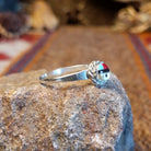 Sterling silver ring with sunface design crafted with turquoise, mother of pearl, black onyx, and coral that is framed by twisted rope detailing.