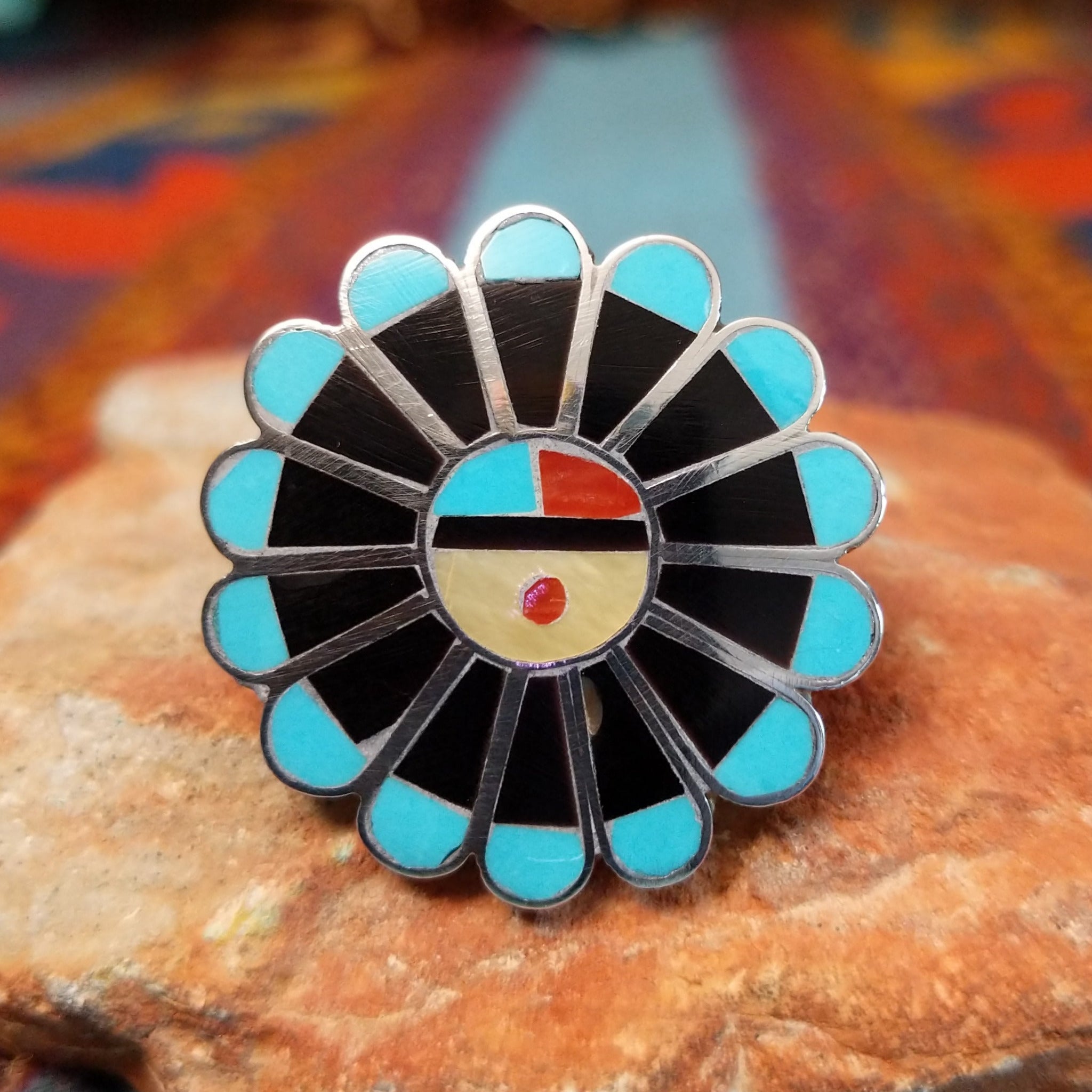 Zuni Sunface Ring by Annie Willie featuring an intricate multicolor inlay Sunface design with turquoise, black, red, and cream-colored accents set in Sterling Silver.