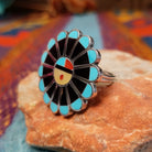 Zuni Sunface Ring by Annie Willie featuring an intricate multicolor inlay Sunface design with turquoise, black, red, and cream-colored accents set in Sterling Silver; side view.