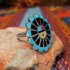Zuni Sunface Ring by Annie Willie featuring an intricate multicolor inlay Sunface design with turquoise, black, red, and cream-colored accents set in Sterling Silver; side view.