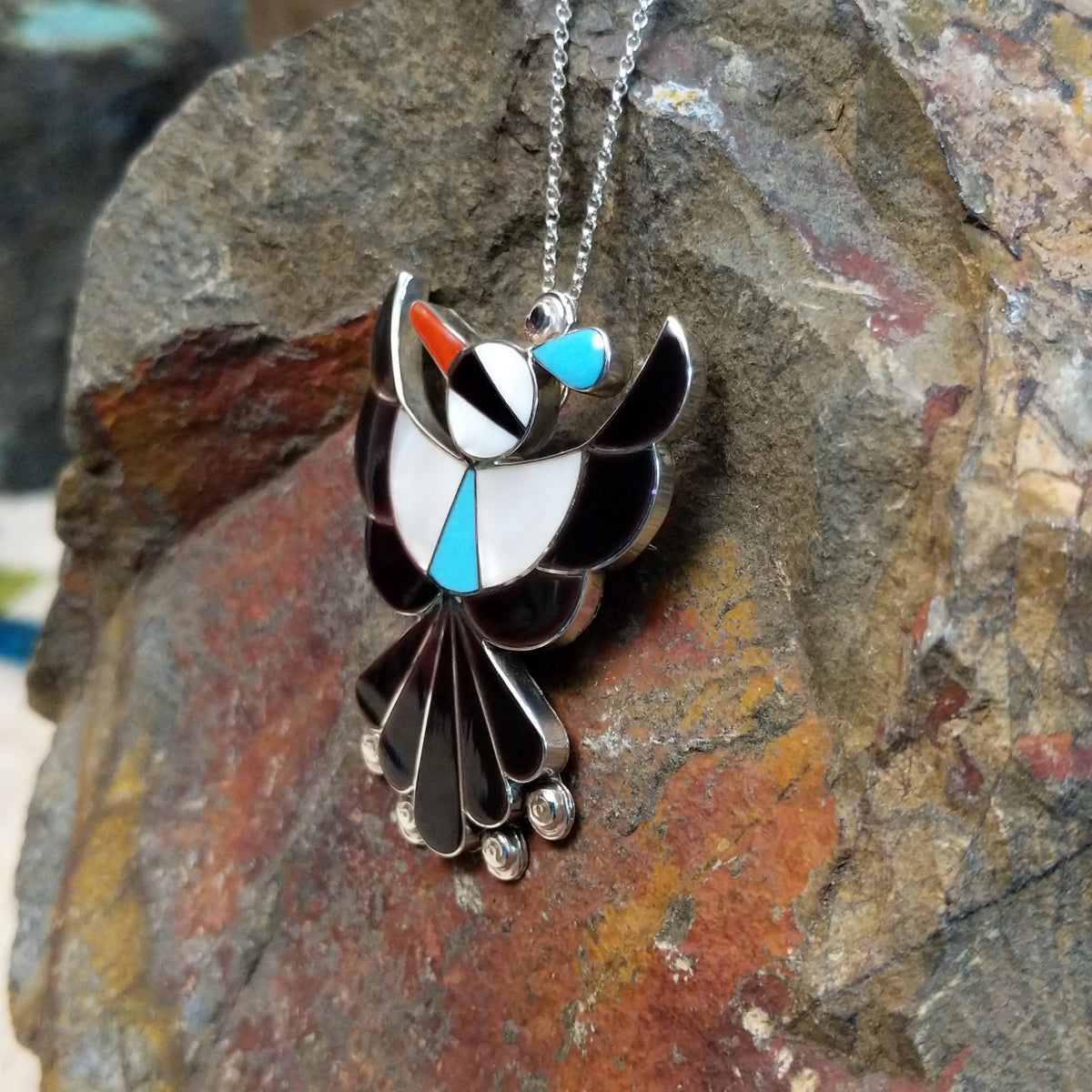 Zuni Thunderbird pendant and pin by Leagus Ahiyite featuring black, white, turquoise, and red stone inlay in a detailed silver Thunderbird design; side view.