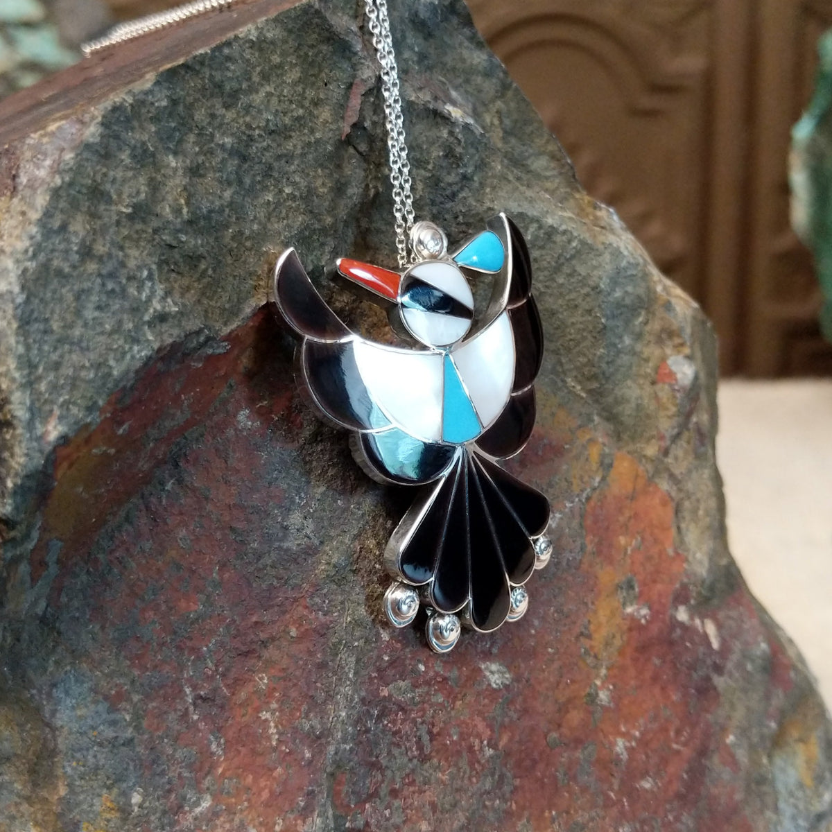 Zuni Thunderbird pendant and pin by Leagus Ahiyite featuring black, white, turquoise, and red stone inlay in a detailed silver Thunderbird design; side view.