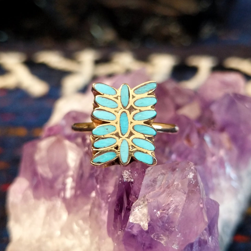 Close-up of the butterfly motif showing elongated turquoise stones set in gold.