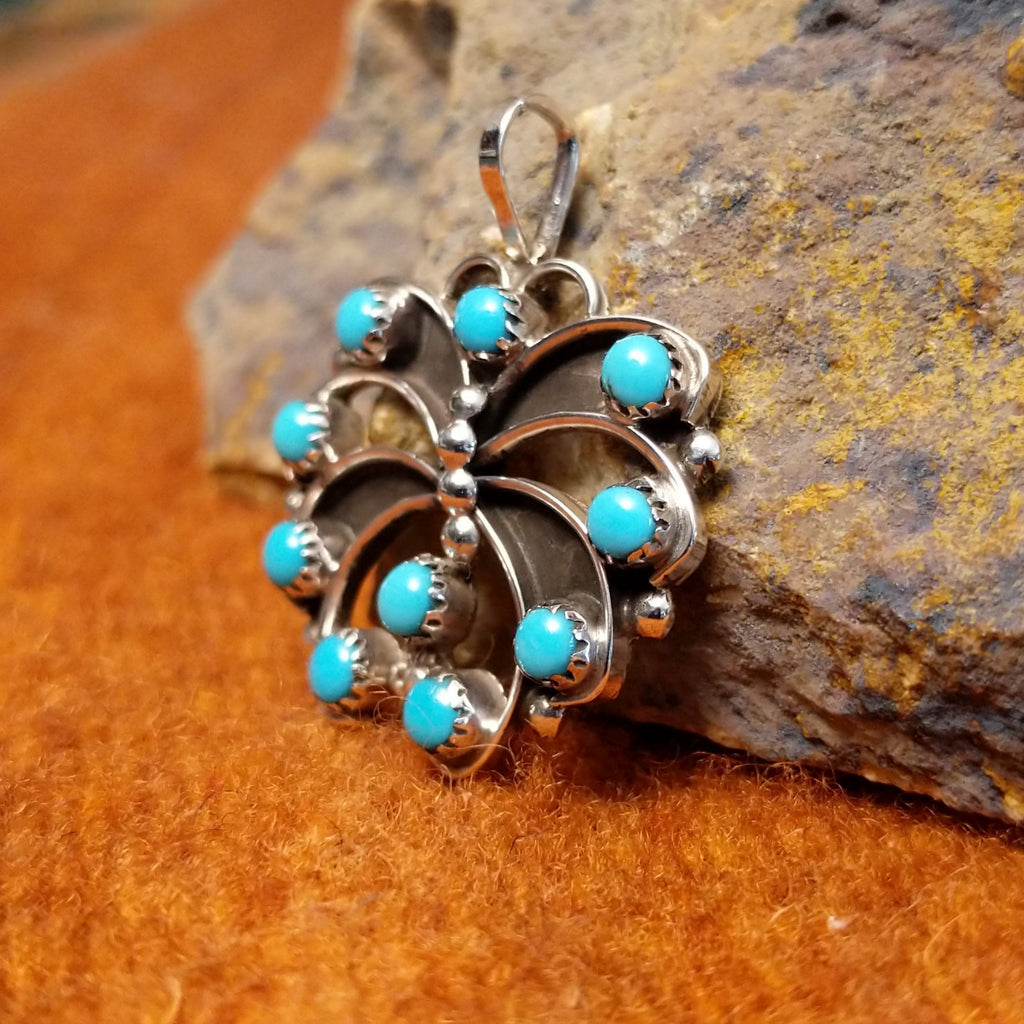Round turquoise set in notched sterling silver bezels making up the wings with silver dotted accents along the body.