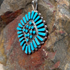 Zuni turquoise cluster pendant by Carlene Hattie featuring tapered and round turquoise stones arranged in an oval cluster with silver bead and twisted-wire detailing; side view.