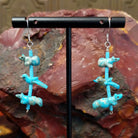 Matching dangle earrings of carved fetishes on heishi beads, suspended from sterling silver hooks.
