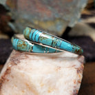 Handcrafted sterling silver Zuni turquoise hoop earrings by Keme Peina, featuring turquoise channel inlay with geometric accents; side view.