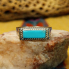 Zuni turquoise rectangle ring by A.Q.J., featuring a rectangular turquoise stone with natural blue tones and matrix patterns set in a handcrafted sterling silver band.