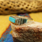 Zuni turquoise rectangle ring by A.Q.J., featuring a rectangular turquoise stone with natural blue tones and matrix patterns set in a handcrafted sterling silver band.  Side view.