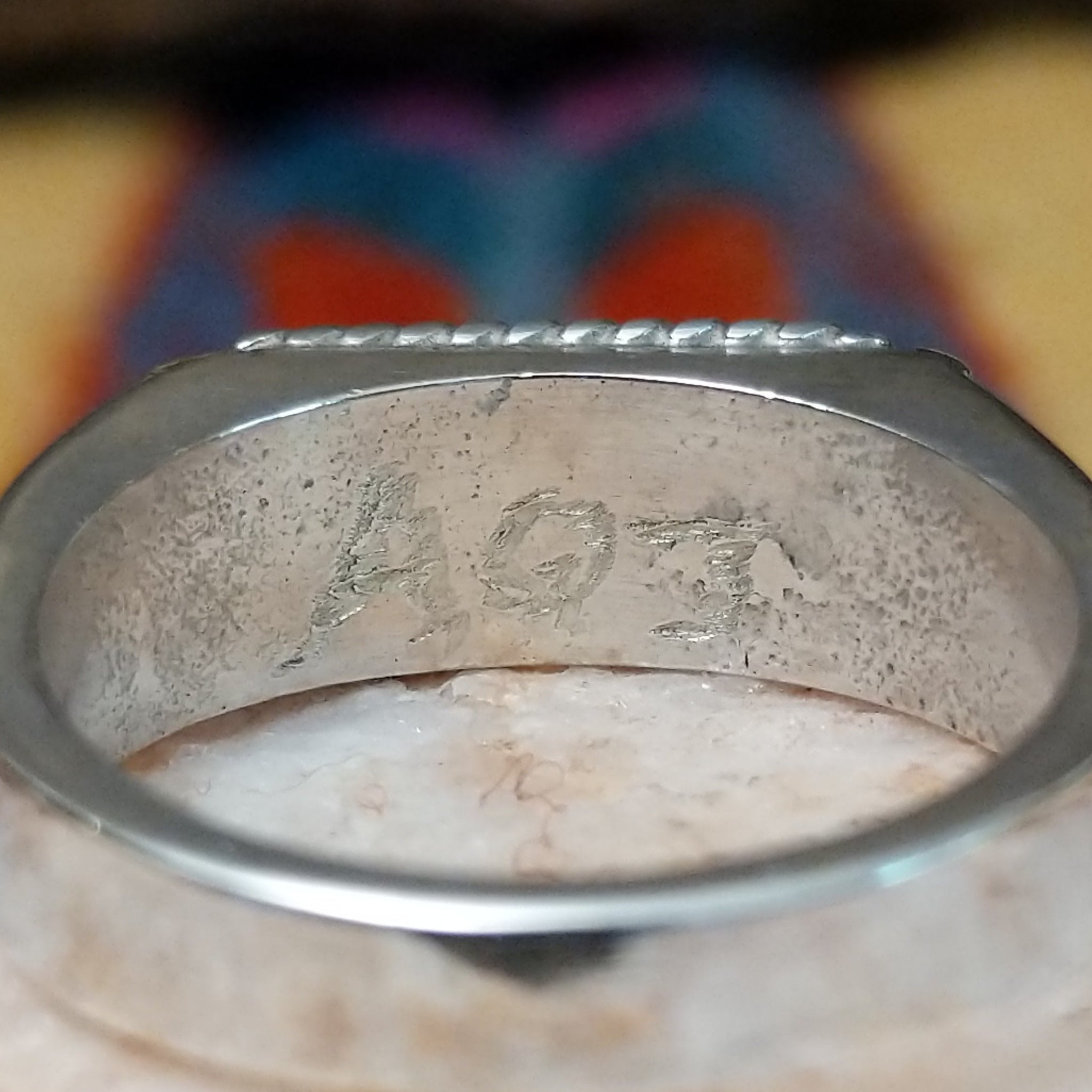 Zuni turquoise rectangle ring by A.Q.J., featuring a rectangular turquoise stone with natural blue tones and matrix patterns set in a handcrafted sterling silver band.  Artisan logo.