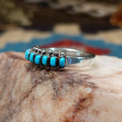 Sterling silver ring with turquoise set in notched bezels, arranged in rows with dotted accents.