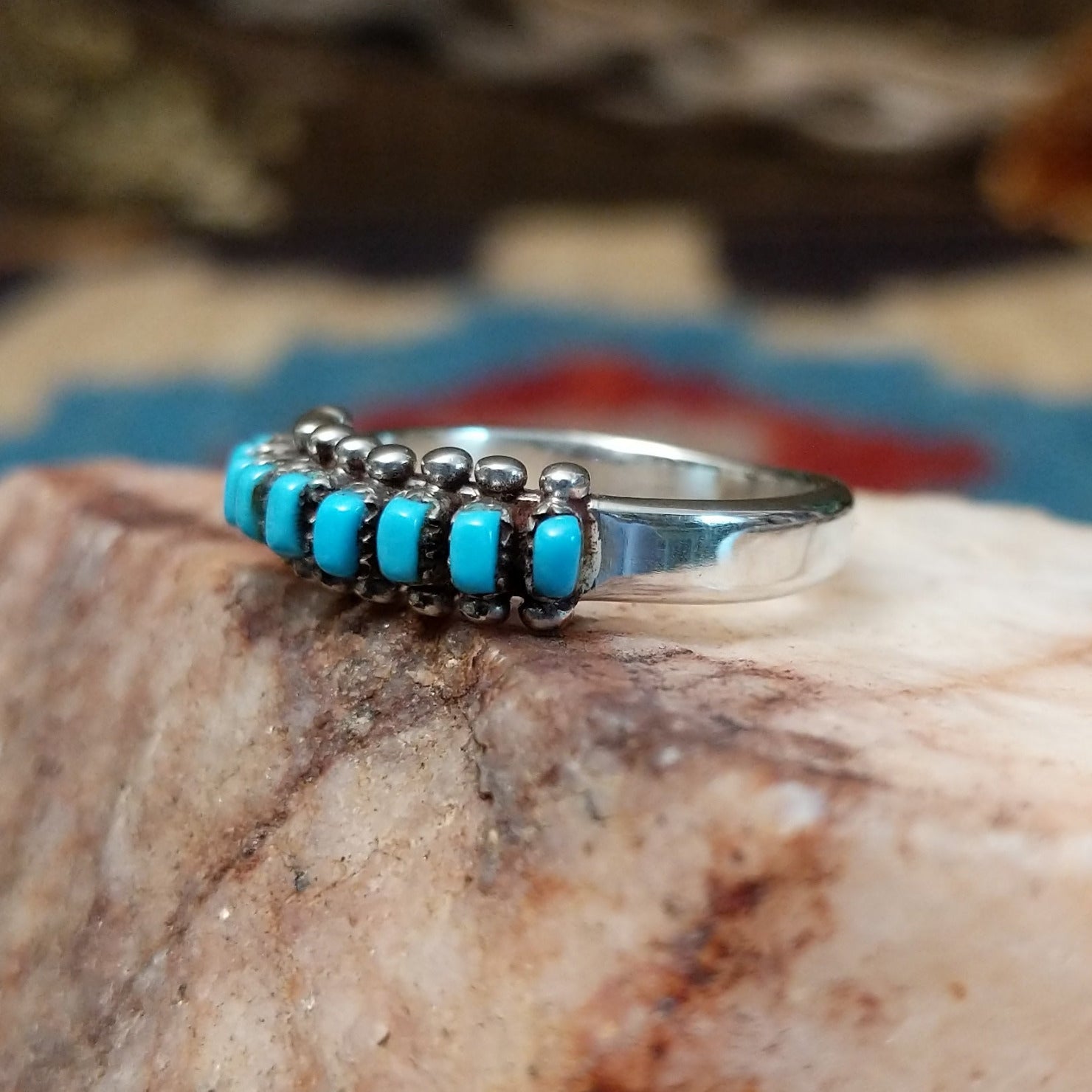 Sterling silver ring with turquoise set in notched bezels, arranged in rows with dotted accents.