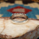 Sterling silver ring with turquoise set in notched bezels, arranged in rows with dotted accents.