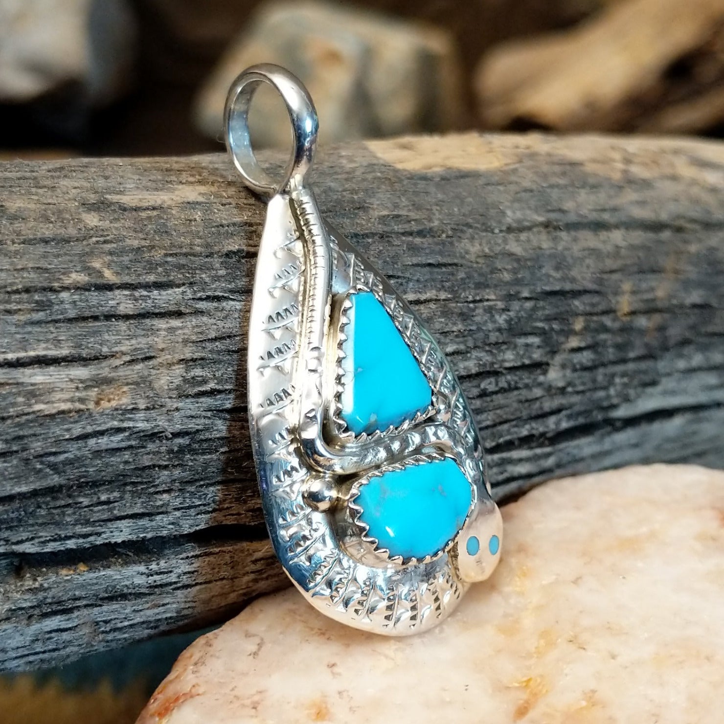 Sterling silver pendant with turquoise set in the bezel, framed by the hammered finish of the silver and snake design.